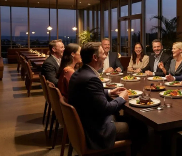 Guests sharing a toast and laughing around a candlelit table at TheKitchenTablle.
